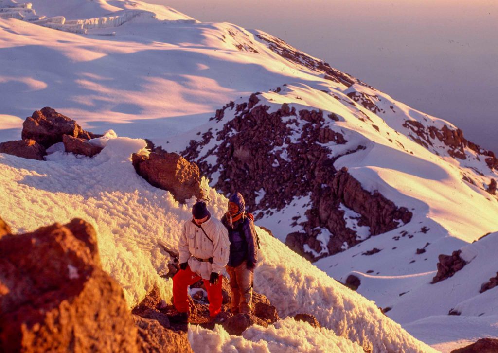 Enkele bergbeklimmers banen zich een weg door de sneeuw van de Kilimanjaro.