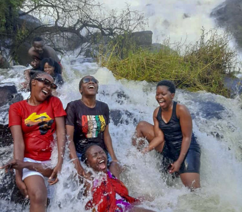 en aantal Oegandezen die met Ssebakaki op pad zijn, dompelen zich onder in het water van een waterval.