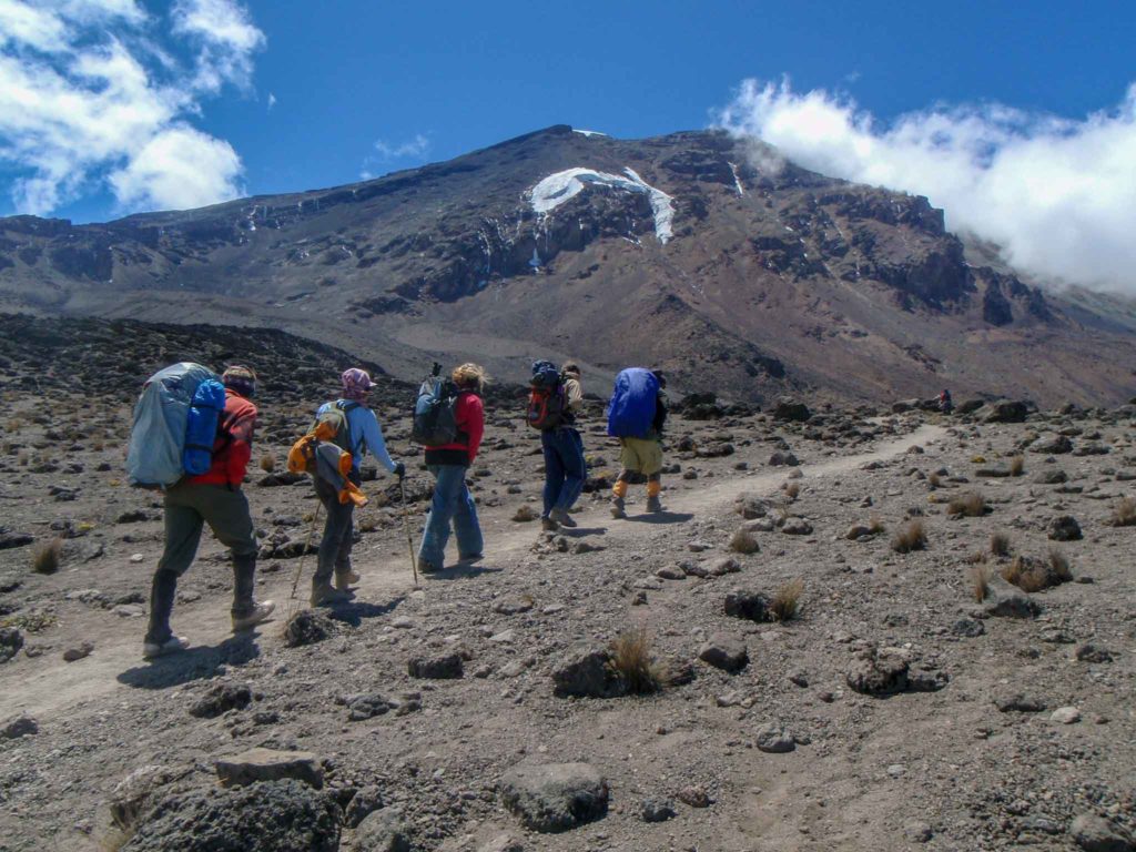 Een groep beklimmers van de Kilimanjaro lopen over een rotsachtig pad naar de piek toe