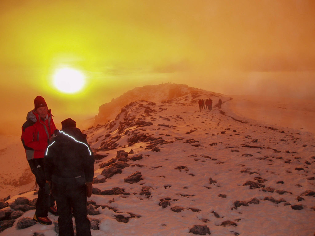 Op de top van mt. Kilimanjaro kijken twee bergbeklimmers naar de opkomende zon