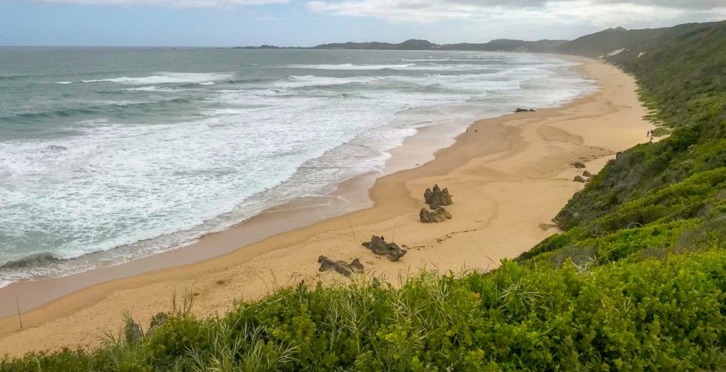 Het uitgestrekte strand van Brenton Beach, van bovenaf gefotografeerd, loopt door tot aan de horizon.