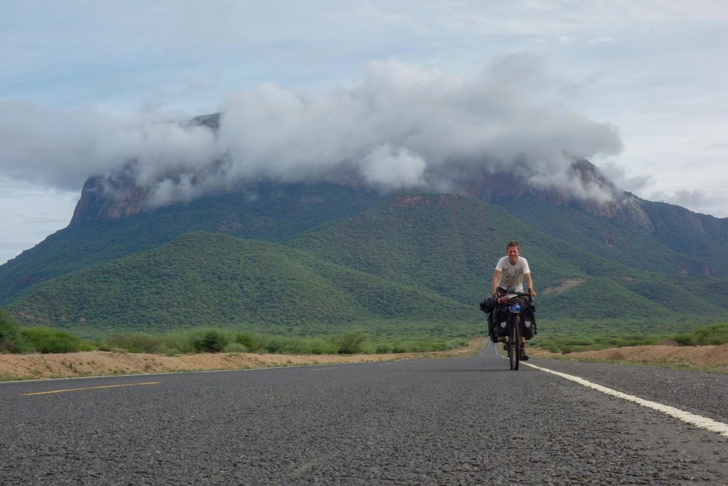 Niels on route to Capetown, on a tarmac road with a big mountain behind him