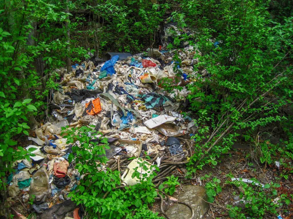 Een grote plastic hoop ligt in het groene bos. 