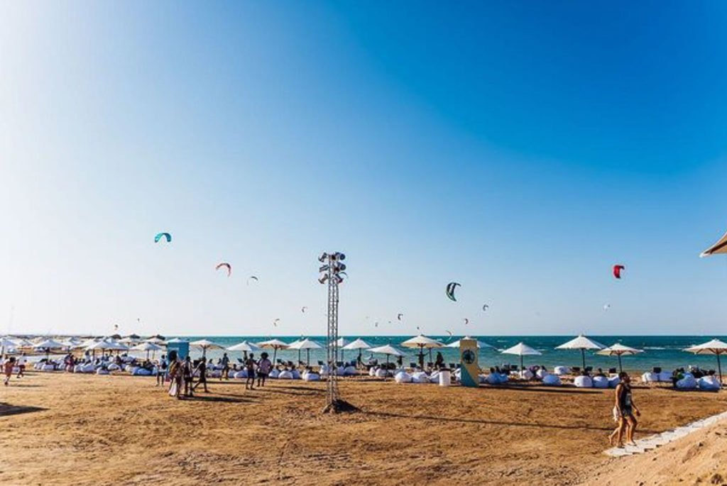 Het strand bij het Sandbox Festival met meerdere kitesurfers te zien in de zee