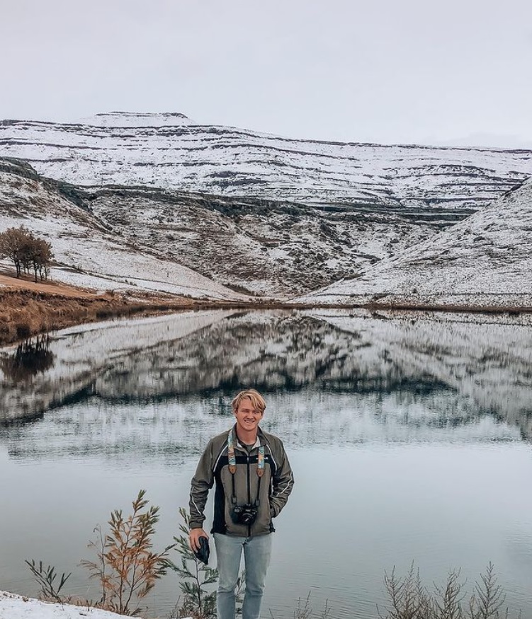 Een fotograaf poseert tegenover het meer in Drakensberg Gardens, met een prachtige reflectie van de omgeving.