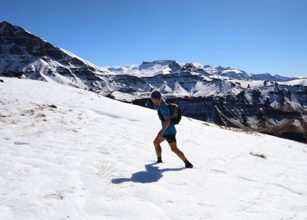 Met zijn enkels diep in de sneeuw loopt deze wandelaar - in korte mouwen en korte broek- door de Drakensbergen