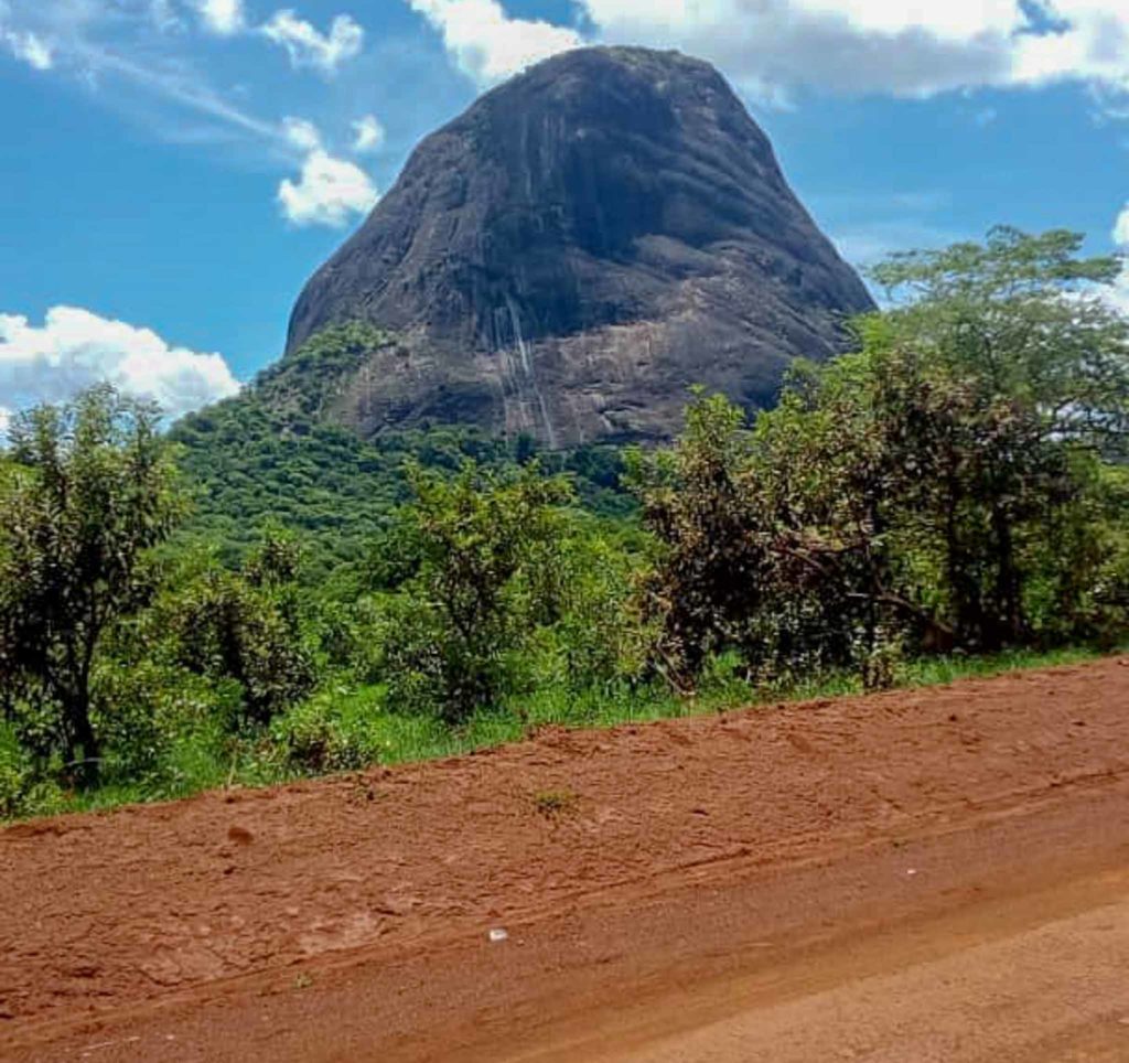 A huge rocky mountain towers above this forest in Uganda